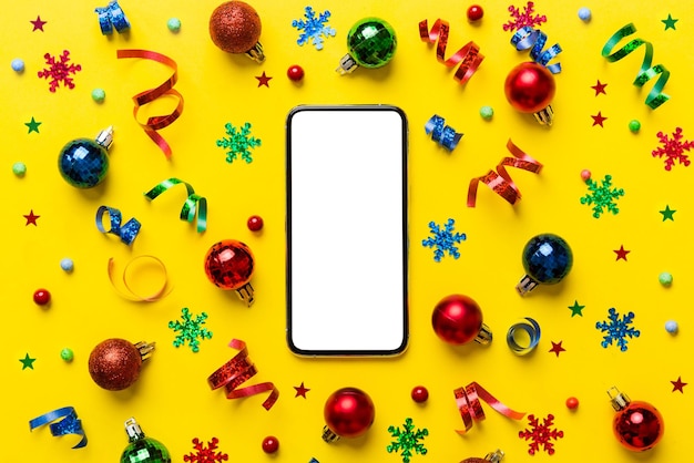 Christmas online shopping from home phone with blank white
display top view smart mobile with copy space on colored background
with christmas decorations balls winter holidays sales
background