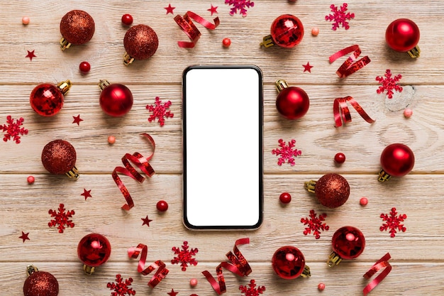 Christmas online shopping from home phone with blank white display top view smart mobile with copy space on colored background with Christmas decorations balls Winter holidays sales background