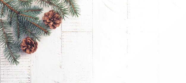 Рождество или новогодний фон. елочные ветви, елочные игрушки, звезды, снежинки и шишки на белом деревянном фоне. выборочный фокус. вид сверху. копировать пространство
