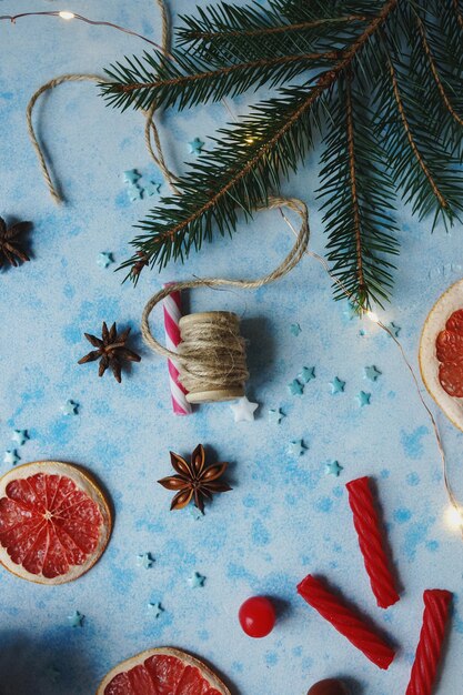 写真 クリスマスや新年の居心地の良い家の装飾は、青いコンクリート背景にオレンジ モミの木とキャンディーを乾燥させます トップ ビューの選択と集中