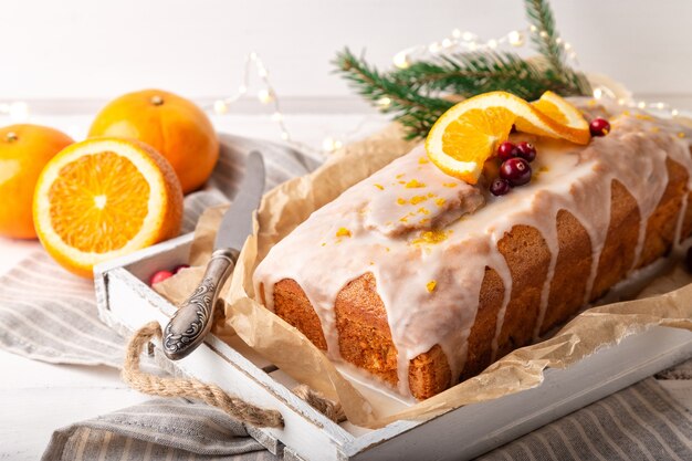 christmas orange cake with cranberries and sugar icing on rustic wooden background