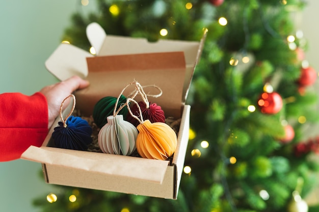 Christmas ornament balls in box with tree and lights in the background Copy space