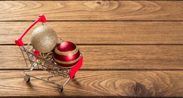 Christmas ornaments balls on miniature shopping cart over the wood for web banner