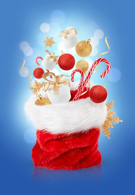 Photo christmas ornaments flying over santa bag on blue background