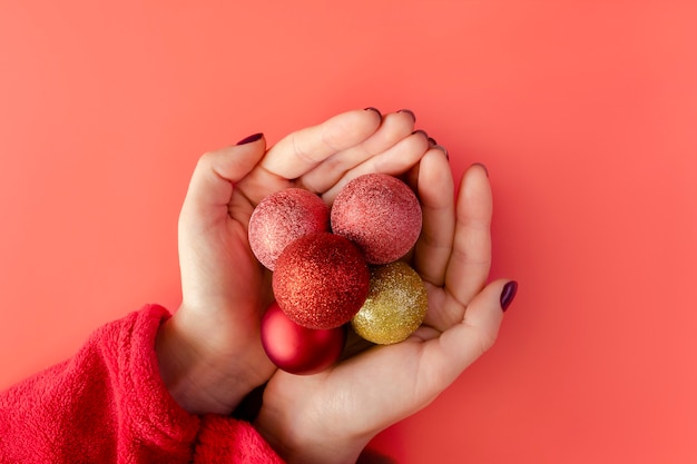 Christmas ornaments in the hands of a girl on a red.