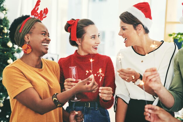 写真 お祝いのシャンパンとお祝いの季節のためのオフィスでのビジネスマンとのクリスマスパーティーと線香花火 多様性のチームワークと従業員との友人と休日の歓声やイベントのためのグラスを飲む