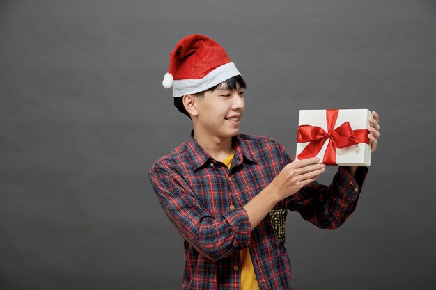 크리스마스 파티와 휴일 개념입니다. 회색 배경에 고립 된 선물 상자 스튜디오 샷을 들고 젊은 아시아 남자