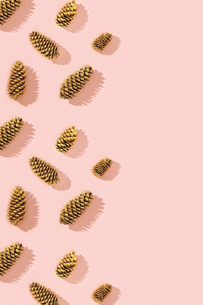 Christmas pattern from natural pine cone painted golden colored on pink