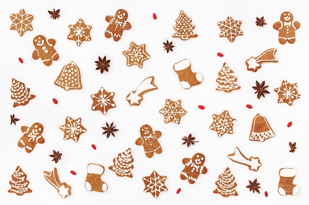 Christmas pattern of gingerbread cookies and spices on white background. Flat lay.