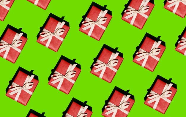 Photo christmas pattern  a pattern from a red box tied with a white ribbon on a light green background