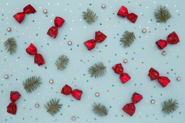 Christmas pattern of red candies, green fir and gold confetti.