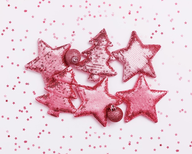 Foto motivo natalizio con brillanti giocattoli di colore magenta a forma di abete di natale e stella con paillettes