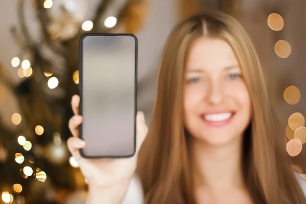 クリスマスの電話と休日の挨拶のコンセプト幸せな笑顔の女性がモバイルスマートの画面を表示しています...