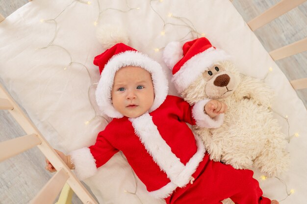 Christmas photo of a baby in a Santa costume lying in a crib at home