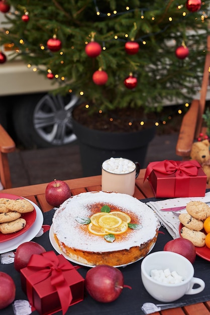 Christmas pie, cocoa with marshmallows and table. Christmas tree background. Van mobile trailer, mobile home, terrace. New Year celebration. Winter holidays. Christmas morning.