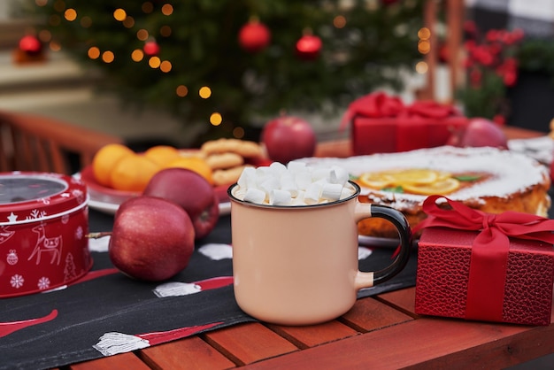 Christmas pie, cocoa with marshmallows and table. christmas\
tree background. van mobile trailer, mobile home, terrace. new year\
celebration. winter holidays. christmas morning.