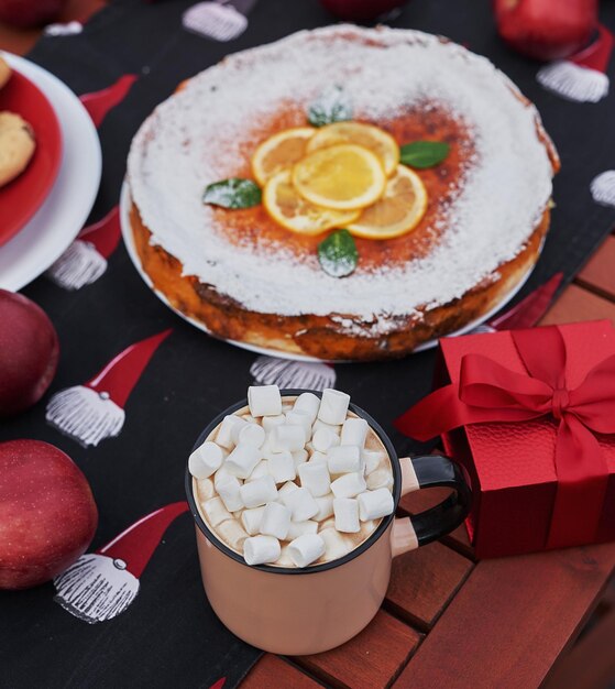 Christmas pie, cocoa with marshmallows and table. Christmas tree background. Van mobile trailer, mobile home, terrace. New Year celebration. Winter holidays. Christmas morning.