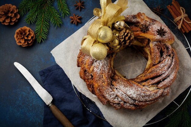 Rotolo di torta di natale con cannella e zucchero a velo su una vecchia superficie di cemento scuro