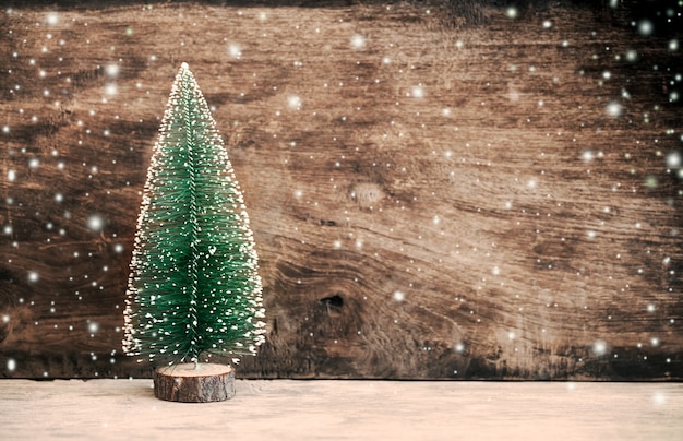 Christmas pine tree on wooden background with snow in vintage color filter