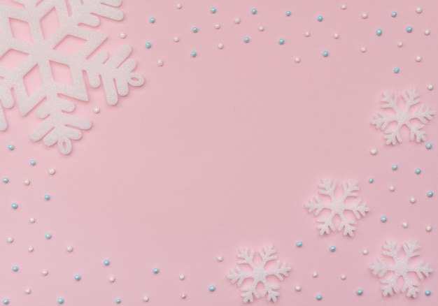 Christmas pink background with white snowflakes and beads. New Year greeting card.