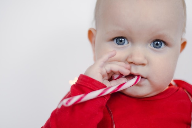 Foto ritratto di natale di un bellissimo bambino che tiene in mano un bastone di caramelle