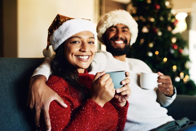 Christmas portrait and coffee with a black couple on a sofa in the living room of a home to relax together Happy smile and love with a man and woman bonding in celebration of the festive season