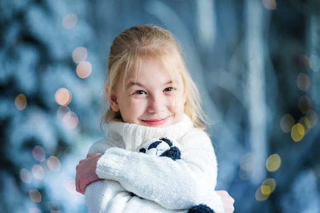 Christmas portrait of happy blonde child girl indoor studio, snowy winter decorated tree