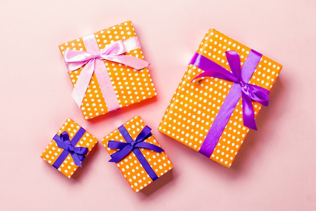 Christmas present box with purple and pink bow on pink 