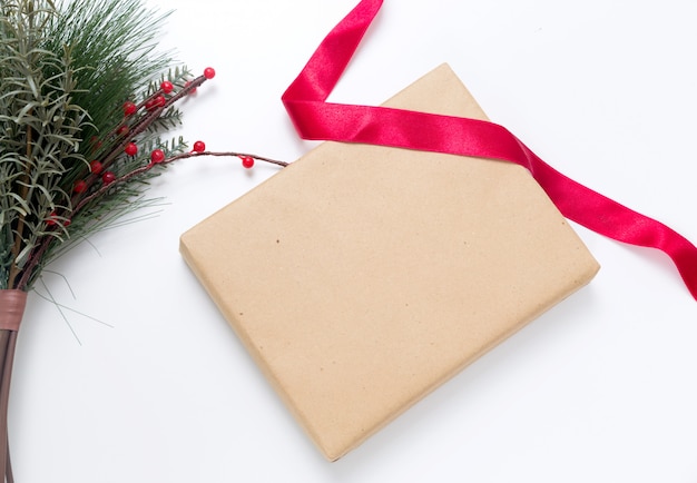 Фото Рождественский подарок в крафт-бумаге с красной лентой