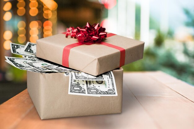 Photo christmas present with red bow wrapped in dollar banknotes