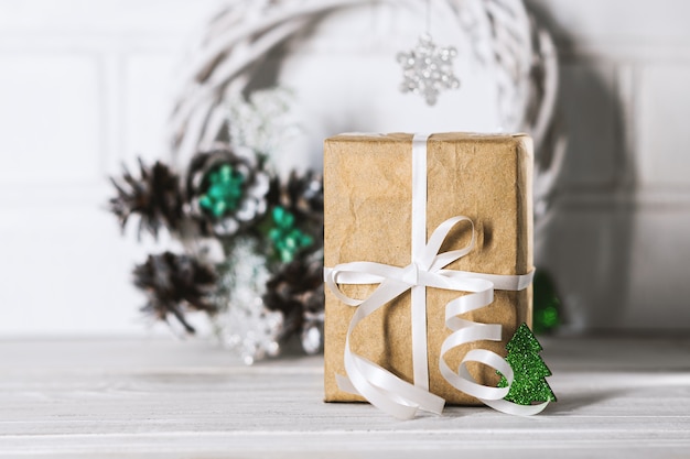 Christmas present with white ribbon and decor green pine on white wooden desk. Christmas gift box. New year present box.