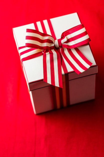 Christmas present wrapped in the box with red and white ribbon.