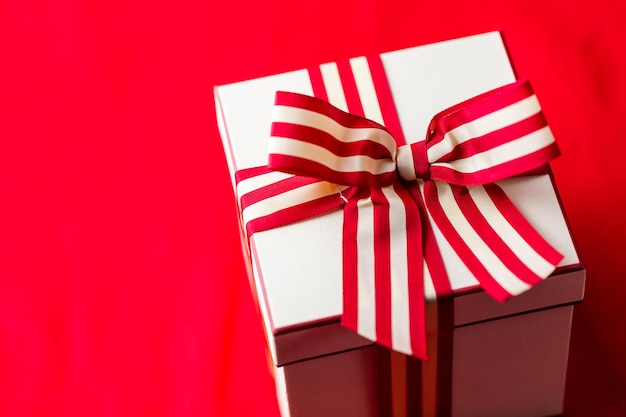 Фото Рождественский подарок, завернутый в коробку с красной и белой лентой.