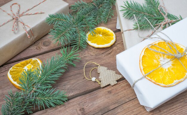 Christmas presents or gift box wrapped in kraft paper with decorations pine cones dry orange