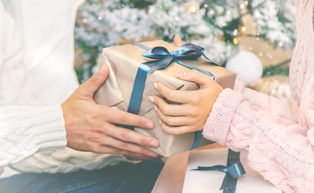 クリスマスは男性と女性の手に贈られます。ホリデー。セレクティブフォーカス。