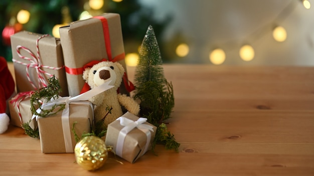 Christmas presents and teddy bear laid on a wooden table.