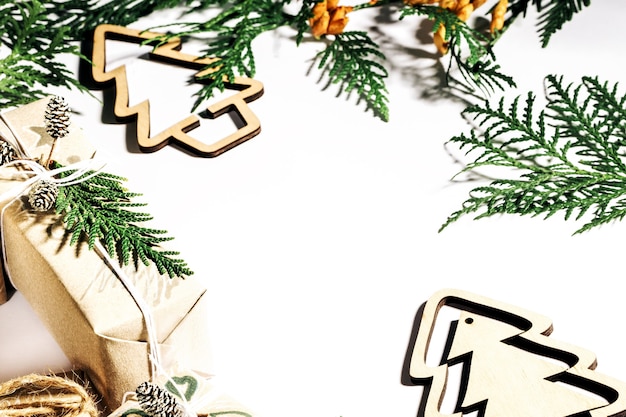 Фото Рождественские подарки с подарочной коробке, украшенной шишками и ветками на белом фоне, подготовка к праздникам. выборочный фокус.