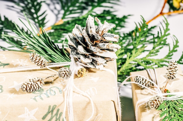 Christmas presents with gift box decorated with pine cones and twigs on a white background, preparation for holidays. Christmas presents and New Year. Handmade. Selective focus,