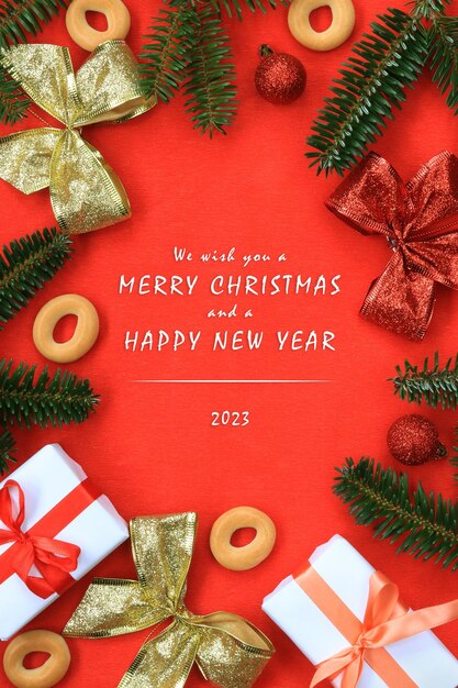 Christmas red background with fir branches. We wish you a Merry Christmas and a Happy New Year 2023