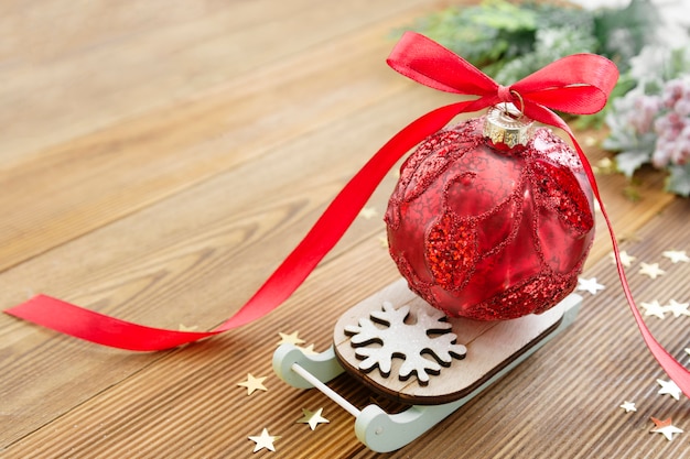 木製の素朴なテーブルの上の赤いリボン弓とそりでクリスマス赤安物の宝石