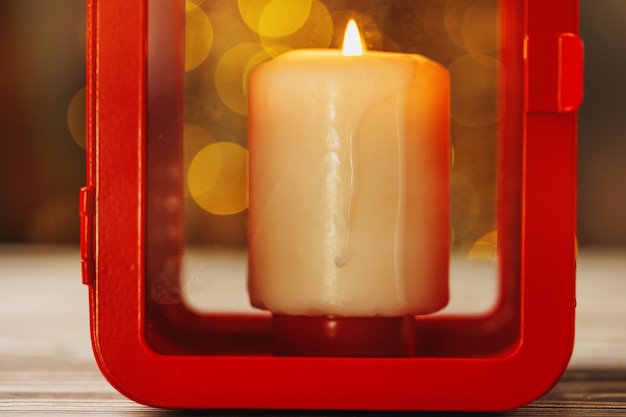 Christmas red lantern with burning candle on wooden table