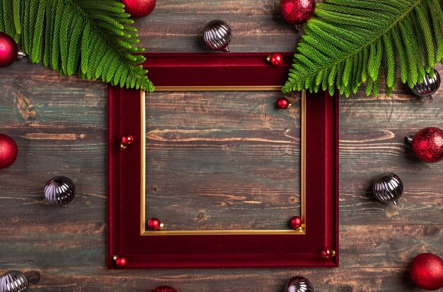 나무 테이블에 소나무 잎과 값싼 물건 장식이 있는 크리스마스 빨간색 액자