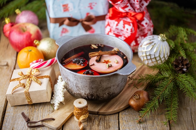 크리스마스 레드 와인 mulled 와인 향신료와 과일 나무 테이블에. 겨울 개념. 크리스마스를위한 전통적인 뜨거운 음료. 감귤, 사과, 냄비에 향미료 mulled 와인.