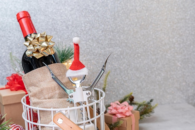 テーブルの背景にサンタ帽子の装飾が施されたクリスマス赤ワインとワインオープナー。