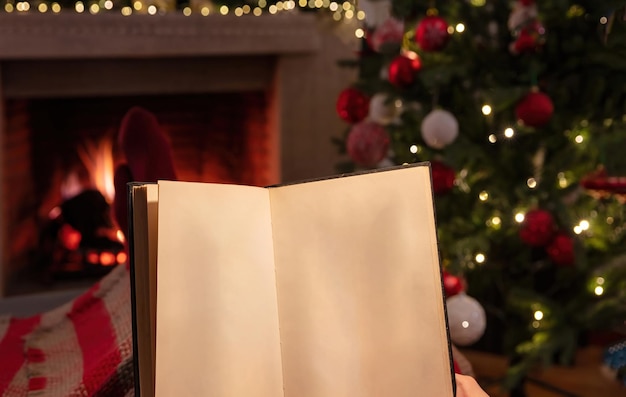 사진 벽난로 배경을 태우는 열린 빈 페이지 책을 들고 집에서 크리스마스 휴식