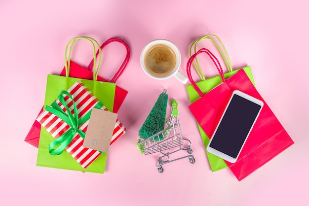 Christmas sale black friday background girl hands holding symbols new year sale - shopping bags, gift boxes, shopping cart, bank card, smartphone, pink colorful background top view