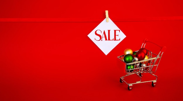 Рождественская распродажа Корзина супермаркета с елочными шарами Текст продажи на белой карточке