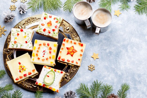 Christmas sandwiches with cheese and vegetables on a plate close up, top view