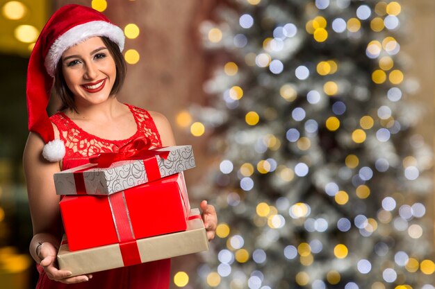 Christmas Santa hat geïsoleerde vrouw portret houden kerstcadeau. Glimlachend gelukkig meisje over Kerstmisachtergrond