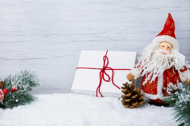 Christmas scene with snow fir branches with cones and Santa Claus toy copy space